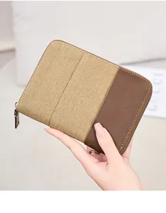 Detail of hand-held khaki canvas and brown faux leather wallet with silver zipper