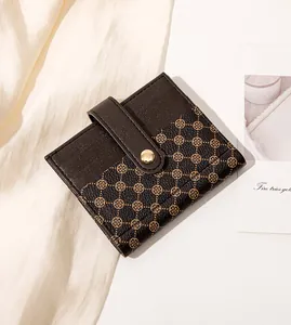 Close-up of compact leather wallet with clover pattern and snap button closure
