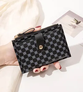 Detail of slim black clover print card holder with gold zipper and leather texture