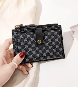 Close-up of black small wallet featuring blue floral patterns and gold button detail