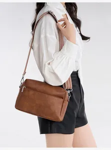 Detail of vintage brown soft leather crossbody bag with geometric wide strap and embossed text