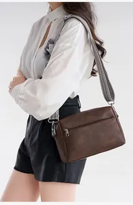 Close-up of vintage dark brown faux leather crossbody bag with geometric woven strap