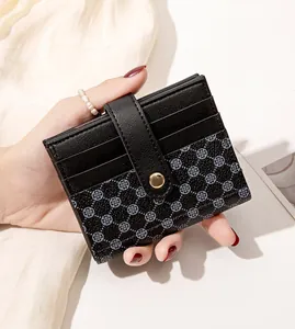 Close-up of a women's black PU leather card wallet with clover print and gold snap closure