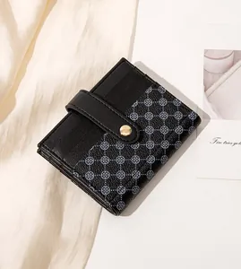 Detail of black leather wallet with clover pattern print and gold snap button closure
