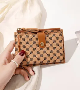 Close-up of tan mini wallet with clover pattern held in hand showing texture