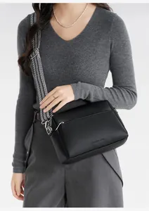 Detail of black faux leather crossbody bag with geometric woven strap and silver hardware