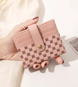 Detail of pink leather card holder featuring clover pattern and gold metal buckle