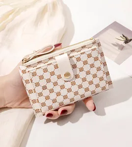 Close-up of slim off-white wallet with clover print and gold zipper detail