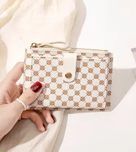 Close-up of stylish floral monogram cream leather mini wallet held in hand