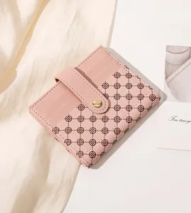 Close-up of pink faux leather wallet with floral patchwork and gold snap button closure