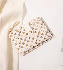 Close-up of cream leather wallet featuring brown floral patterns and golden hardware