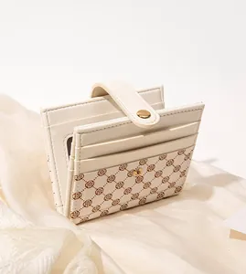 Close-up of cream leather short wallet with brown clover patterns and interior card slots