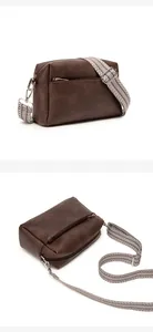 Detail of dark brown leather crossbody bag featuring geometric patterned wide strap