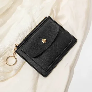 Détail du petit porte-monnaie en cuir noir avec zip doré et anneau sur dentelle blanche