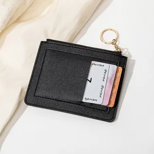 Détail du porte-cartes en cuir noir avec fermeture éclair dorée et anneau porte-clés