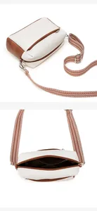 Detail of soft white leather crossbody bag with brown trim and geometric strap