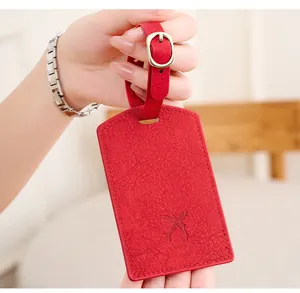 Close-up of red PU leather luggage tag with pebble texture and gold metal buckle
