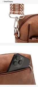 Detail display of brown faux leather bag with patterned wide strap and phone pocket