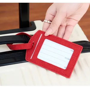Detail of red PU leather luggage tag with transparent ID window on suitcase handle