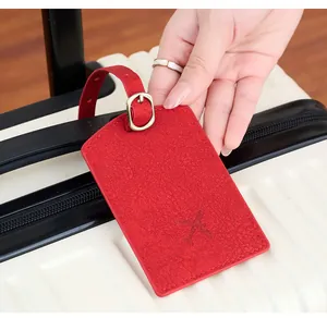 Close-up of red leather luggage tag with aircraft embossing and gold metal buckle