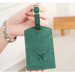 Close-up of forest green PU leather luggage tag with embossed airplane and metal buckle