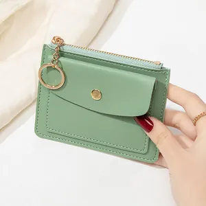 Détail d'un porte-cartes mince vert menthe avec fermeture éclair et porte-clés doré