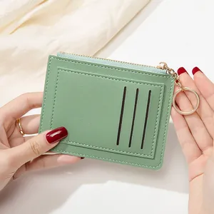 Détail d'un porte-cartes mince vert clair avec trois fentes, fermeture éclair et porte-clés