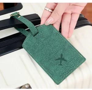 Close-up of green PU leather luggage tag with airplane icon on suitcase handle