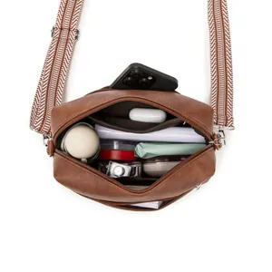 Brown soft leather crossbody bag with geometric strap and organized interior storage