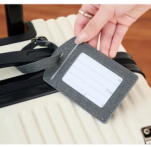 Close-up of grey PU leather luggage tag with name card attached to a suitcase