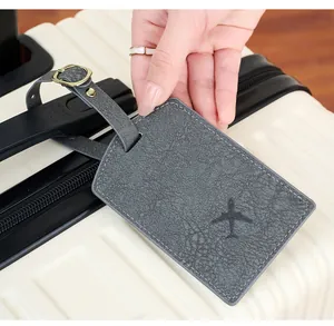 Detail of grey PU leather luggage tag with airplane icon on suitcase handle