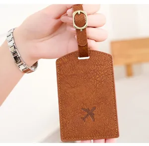 Detail of dark brown faux leather luggage tag featuring airplane stamp and metal buckle