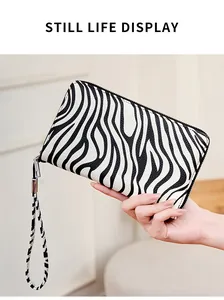 Detalle de cartera larga de cebra con bloqueo RFID y correa de muñeca de cuero texturizado