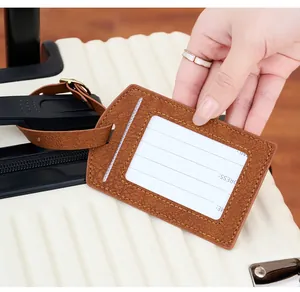 Close-up of brown PU leather luggage tag with lychee texture and name ID card on a suitcase