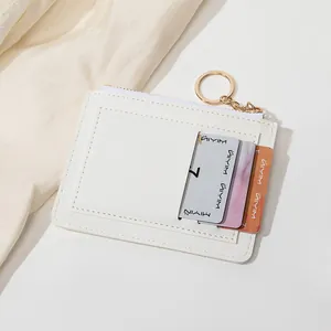 Détail macro du portefeuille blanc mince avec coutures, fentes pour cartes et porte-clés doré