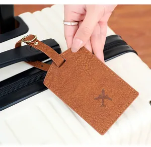 Close-up of brown PU leather luggage tag with plane icon on a white suitcase handle