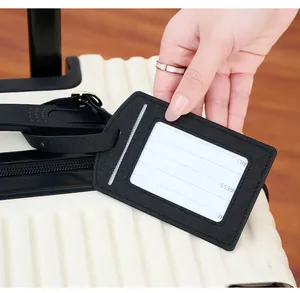 Detail of black PU leather luggage tag with address card on a beige suitcase