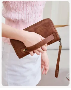 Dettaglio di un portafoglio RFID in pelle marrone con cinturino tenuto da modella