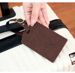 Close-up of brown PU leather luggage tag with airplane icon on a white suitcase