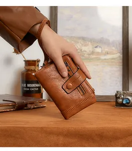 Detailed view of brown leather wallet with wrist strap held by model in retro style
