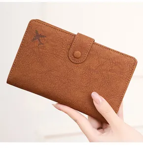 Detail of brown RFID leather passport holder featuring airplane embossing and snap closure