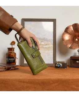 Detail view of the olive green leather wallet with zipper pocket and wrist strap handle
