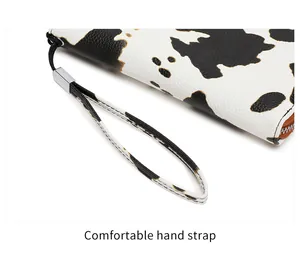 Detalle de la cartera con estampado de vaca, cuero texturizado y correa de mano