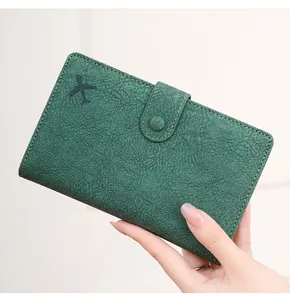 Detail of dark green textured leather passport wallet with airplane embossing and buckle