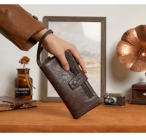 Detail view of brown pebbled leather long wallet with zipper pockets and wrist strap
