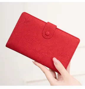 Detail of red RFID travel wallet featuring an embossed airplane and secure button snap closure