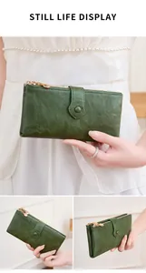 Detail of dark green leather wallet with gold double zippers and textured pebble grain