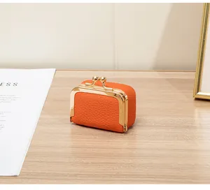 Détail macro du mini porte-monnaie en cuir grainé orange avec fermoir métallique doré