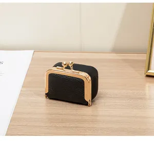 Gros plan d'une mini pochette à bijoux en cuir noir avec fermoir doré métallisé