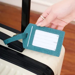 Teal PU leather luggage tag with adjustable strap on white suitcase for travel